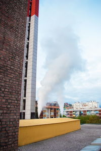 Smoke emitting from factory against sky in city