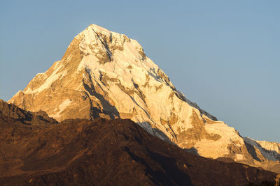 Low angle view of snowcapped mountain against clear sky