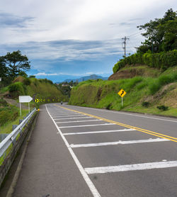 Road by trees against sky