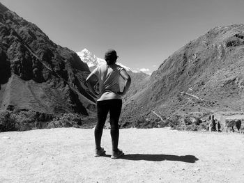 Full length rear view of woman standing against mountains