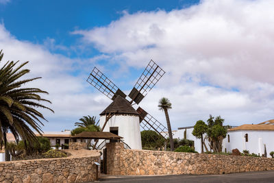 Traditional windmill by building against sky