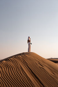 Low angle view of man standing on beach against clear sky