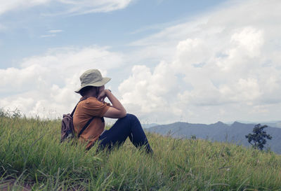 Full length of woman sitting on grass against sky