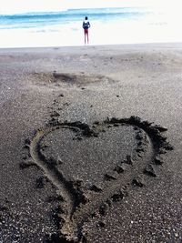 Full length of man making heart shape on beach