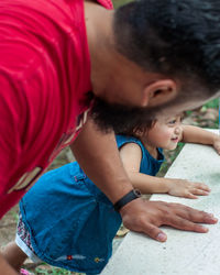 Rear view of father and toddler daughter outdoors.