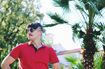 Young happy handsome bearded man, tourist sitting in green park. summer vacation. sunglasses.