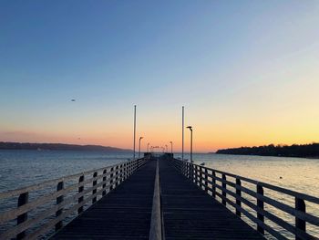 Pier over sea against clear sky during sunset