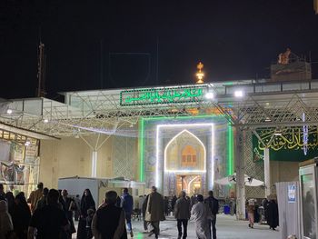 Group of people against illuminated buildings at night