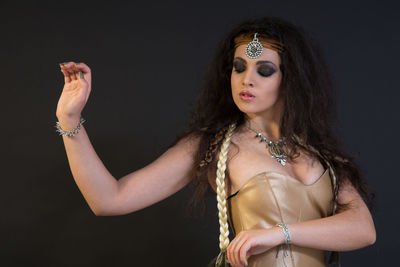 Beautiful young woman dancing against black background