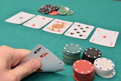 Cropped hand holding cards by gambling chips at table in casino