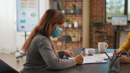 Young woman using mobile phone while sitting in cafe