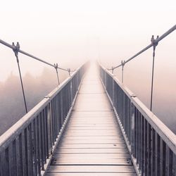 Footbridge against sky during foggy weather