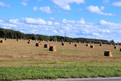 Hay bales on field against sky