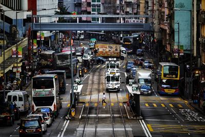 A woman crossing the street where tram is passing by, a typical scene in hong kong island.