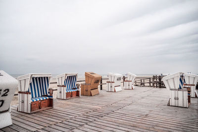 Hooded chairs on beach against sky