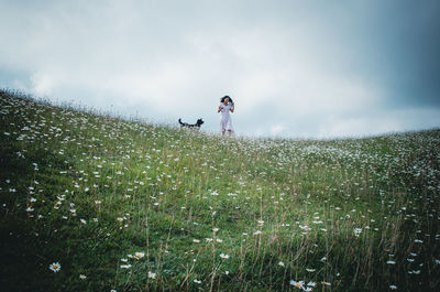 Woman and dog on field against sky