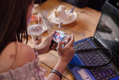 High angle view of woman photographing smart phone on table