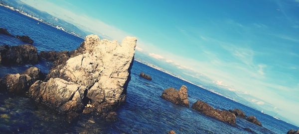 Panoramic view of rocks on beach against blue sky