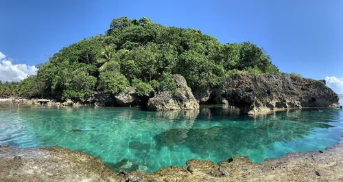 Panoramic shot of rocks by sea against blue sky