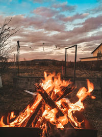 Bonfire on log against sky during sunset