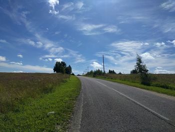 Road amidst agricultural field against sky