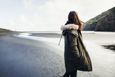 Rear view of woman standing at beach