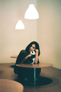 Young woman sitting on table at home