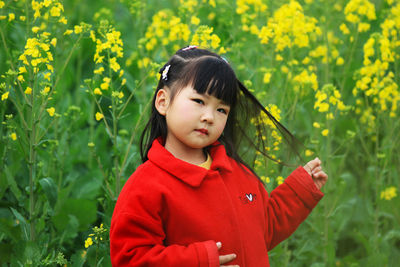 Portrait of cute girl standing against yellow flowering plants