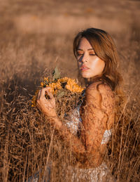 Young woman looking away while relaxing on field