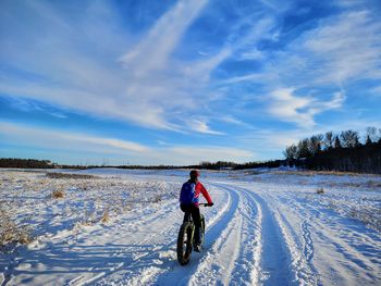 Full length of man riding bicycle on snow field