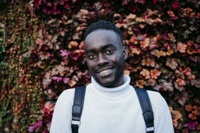 Portrait of young man standing against plants