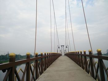 Footbridge over sea against sky