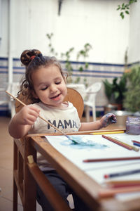 Cute girl looking at camera while sitting on table