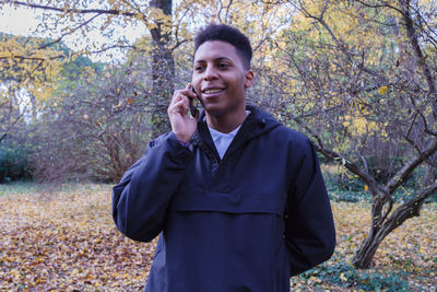 Young man using smart phone while standing on field