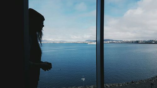 Side view of woman with harbor in background