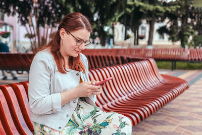 Young woman using mobile phone while sitting on sofa at home