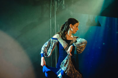 Side view of young woman standing at night