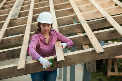 Portrait of woman wearing hat while standing on wood at construction site