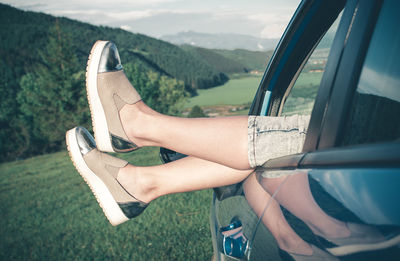 Low section of woman in car against sky