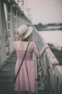 Rear view of woman standing by railing on footbridge