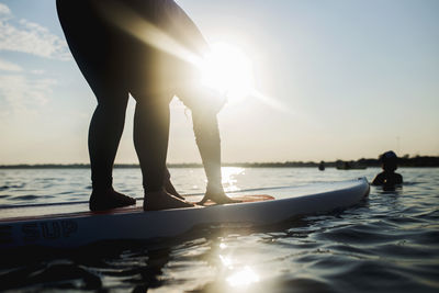 Low section of men standing in sea