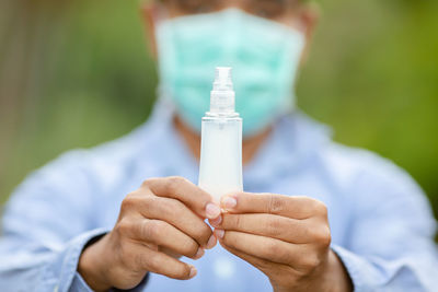 Midsection of man holding glass bottle