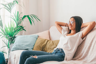 Smiling woman resting on sofa at home