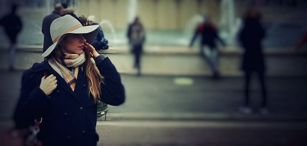 Young woman wearing hat standing on street