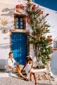 Woman sitting on plant against building