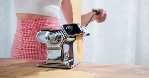 A woman is using a pasta maker on table