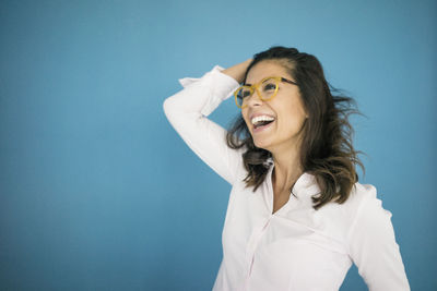 Portrait of laughing woman wearing glasses in front of blue background