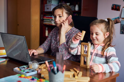 Women and daughter by table at home