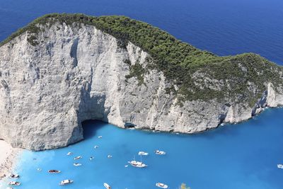 Aerial view of rocks by sea against blue sky