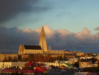 Buildings in city against cloudy sky